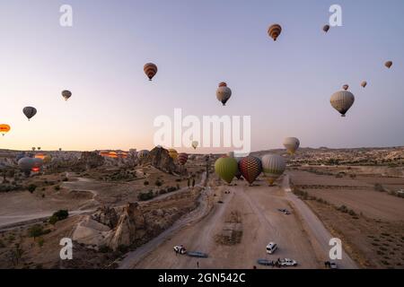 Kappadokien, Türkei - 14. September 2021: Weitwinkelaufnahme von bunten Heißluftballons, die am frühen Morgen in Goreme am Himmel schweben Stockfoto