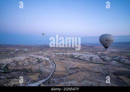 Kappadokien, Türkei - 14. September 2021: Weitwinkelaufnahme von bunten Heißluftballons, die am frühen Morgen bei Sonnenaufgang zusammen am Himmel schweben Stockfoto