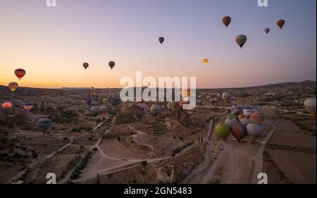 Kappadokien, Türkei - 14. September 2021: Weitwinkel-Panoramaaufnahme von bunten Heißluftballons, die am frühen Morgen gemeinsam am Himmel schweben Stockfoto