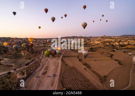 Kappadokien, Türkei - 14. September 2021: Weitwinkelaufnahme von bunten Heißluftballons, die am frühen Morgen in Goreme am Himmel schweben Stockfoto