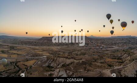 Kappadokien, Türkei - 14. September 2021: Weitwinkel-Panorama-Luftaufnahme von bunten Heißluftballons, die am frühen Morgen gemeinsam am Himmel schweben Stockfoto