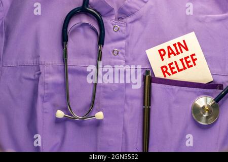 Symbol für Schmerzlinderung. Medizinische Uniform, weiße Karte mit Worten Schmerzlinderung, metallischer Stift und Stethoskop. Medizin und Schmerzlinderung Konzept. Stockfoto