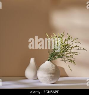 Meer-Lavendel in einer weißen Keramikvase an einer beigen Wand Stockfoto