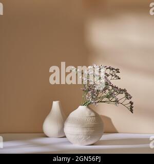 Marsh-Rosmarin in einer weißen Keramikvase an einer beigen Wand Stockfoto
