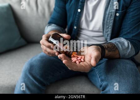 Mann gießt Kapseln aus der Flasche, halten Pillen auf der Hand. Überdosis von Medikamenten und Schmerzen Stockfoto