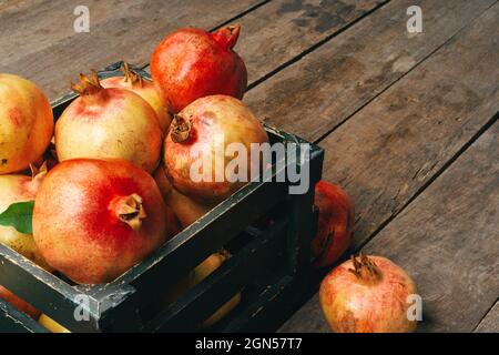 Frische Granatäpfel in einer alten Kiste auf Holzhintergrund Stockfoto