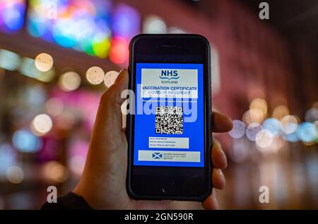 Glasgow, Schottland, Großbritannien. September 2021. Eine Gruppe, die Nachtclubs vertritt, wird eine rechtliche Anfechtung der Pläne der schottischen Regierung für Impfpass einleiten.die erste Ministerin Nicola Sturgeon sagte, das Programm würde dazu beitragen, die Übertragung des Virus zu reduzieren und die Clubs offen zu halten. Jedoch sagte die Night Time Industries Association Scotland (NTIA), dass es „schwerwiegende Fehler“ bei den Plänen gebe und hat Anwälte angewiesen, gegen die schottische Regierung vorzugehen. PIC; Mock up der möglichen schottischen Regierung Covid-19 App vor dem Hintergrund der Nacht Zeit Glasgow Stadtzentrum. Iain Masterton/Alamy Live News Stockfoto