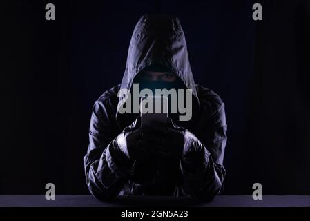 Hooded Cyber Crime Hacker mit Handy-Internet-Hacking in den Cyberspace, online persönliche Daten-Sicherheitskonzept Stockfoto