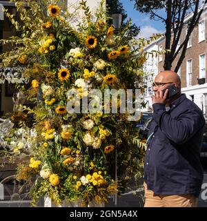 London, Großbritannien. September 2021. Ein Mann geht an der lebhaften Ausstellung der gelben Blumen im MOSCOT an der Kings Road vorbei. Chelsea in Bloom ist ein jährliches Festival und Wettbewerb mit Blumen- und Pflanzenausstellungen der teilnehmenden Geschäfte, Restaurants und anderer Unternehmen in Chelsea, das dieses Jahr vom 20. Bis 25. September stattfindet. Kredit: Imageplotter/Alamy Live Nachrichten Stockfoto