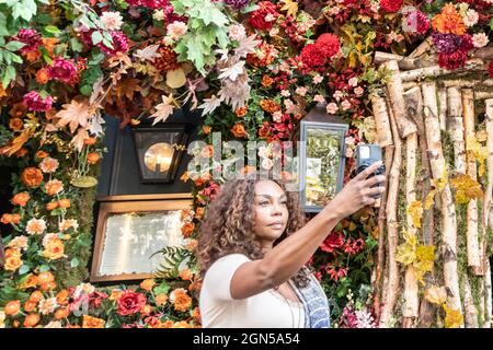 London, Großbritannien. September 2021. Eine Frau macht Selfies mit der sehr farbenfrohen Darstellung im Restaurant Ivy an der King´s Road. Chelsea in Bloom ist ein jährliches Festival und Wettbewerb mit Blumen- und Pflanzenausstellungen der teilnehmenden Geschäfte, Restaurants und anderer Unternehmen in Chelsea, das dieses Jahr vom 20. Bis 25. September stattfindet. Kredit: Imageplotter/Alamy Live Nachrichten Stockfoto