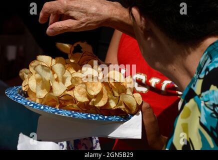 Eine Frau genießt es, auf der jährlichen Fiesta de Santa Fe in Santa Fe, New Mexico, einen Teller mit Pommes Frites oder Kartoffelchips zu essen. Stockfoto