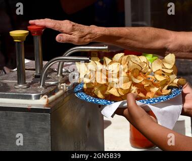 Eine Frau legt Catsup oder Ketchup auf einen Teller mit Pommes frites, die von einem Lebensmittelhändler auf der jährlichen Fiesta de Santa Fe in Santa Fe, New Mexico, gekauft wurden. Stockfoto