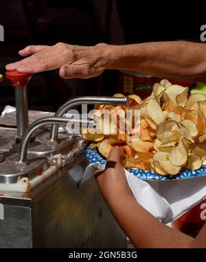 Eine Frau legt Catsup oder Ketchup auf einen Teller mit Pommes frites, die von einem Lebensmittelhändler auf der jährlichen Fiesta de Santa Fe in Santa Fe, New Mexico, gekauft wurden. Stockfoto