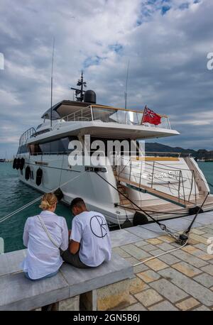 Pärchen am Kai, Pärchen am Meer, Luxus-Motorboot, Luxus-Boot, gemischtes Rennpaar im Urlaub, großes Motorboot, Liebe Stockfoto