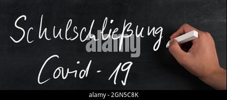 Schule geschlossen, weil Covid-19 in deutscher Sprache auf einer Tafel steht Stockfoto