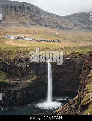 Mulafossur Wasserfall mit dem Dorf Gasadalur auf den Färöer Inseln. Wasserfall trifft auf das Meer Stockfoto