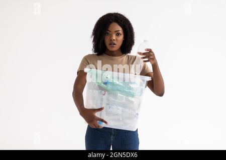 Recycling, Abfallsortierung und Nachhaltigkeitskonzept - lächelnde junge afroamerikanische Frau mit Plastikflaschen auf weißem Hintergrund Stockfoto