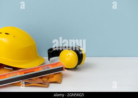 HardHat mit Ohrenschützern und Baumaterial auf farbigem Hintergrund Stockfoto