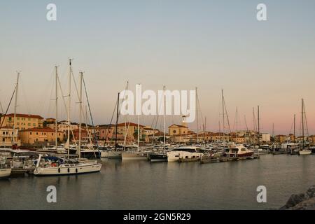 Panoramablick auf den Touristenhafen des Fischerdorfes an der toskanischen Küste mit angedockten Yachten und Segelbooten bei Sonnenuntergang, San Vincenzo, Livorno Stockfoto