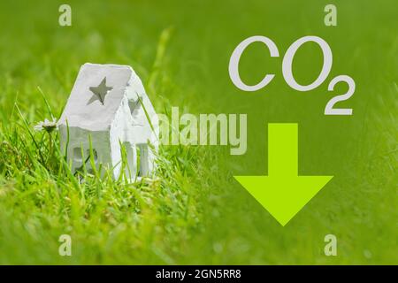 Reduzierung der Kohlendioxidemissionen, Begrenzung der globalen Erwärmung und Konzept des Klimawandels. Weißes Haus, CO2-Schild und grüner Pfeil nach unten Stockfoto