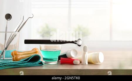 Professionelle Tierarzneimittel und Zubehör zur Reinigung von Eckzähnen auf Holztisch und Fensterhintergrund. Vorderansicht. Horizontale Zusammensetzung. Stockfoto