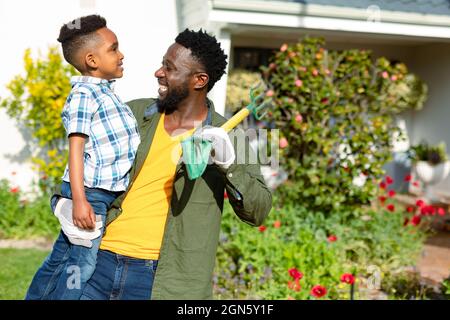 Glücklicher afroamerikanischer Vater, der seinen Sohn und seine Pitchfork hält Stockfoto