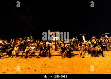 Sitges, Spanien. September 2021. Die Zuschauer versammeln sich an einem Wellenbrecher, um dem traditionellen Feuerwerk in der Kirche „San Bartolomeu“ während der kleinen „Festa Major“ von Sitges, „Santa Tecla“, zu folgen. Die diesjährige 'Corona Edition' nahm eine sehr reduzierte Form an und ließ den Strand fast leer. Quelle: Matthias Oesterle/Alamy Live News Stockfoto