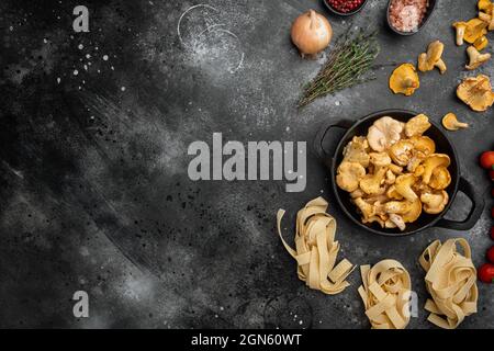 Rohe Tagliatelle mit Pfifferlinge Pilze Zutaten Set, auf schwarzem rustikalem Tischhintergrund, Draufsicht flach liegend, mit Platz für Text Stockfoto