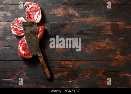 Rindfleisch marmoriert Steak Chuck Augenrolle und Entrecote. Ösenrolle auf dem Schneidbrett aufziehen. Dunkler Holzhintergrund. Draufsicht Stockfoto