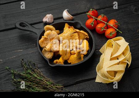 Pasta-Zutaten mit Rohpilzen Pfifferlinge Set, auf schwarzem Holztisch Hintergrund Stockfoto
