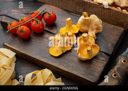 Rohe Tagliatelle mit Zutaten für Pfifferlinge, auf altem dunklen Holztisch Stockfoto