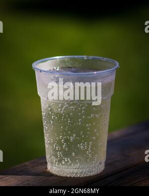 Der vertikale Schuss der Tasse des sauberen Wassers auf der hölzernen Oberfläche Stockfoto