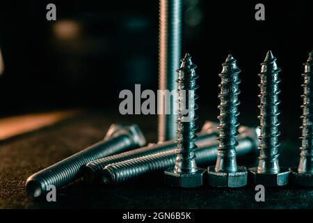 Nahaufnahme der silbernen Metallschrauben auf der schwarzen Oberfläche Stockfoto