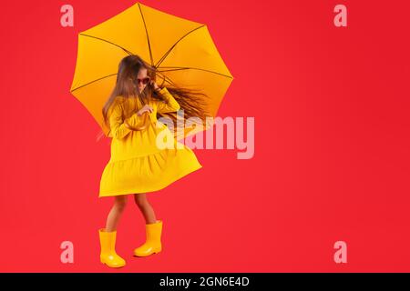 Glücklich emotionale Mädchen lachen mit Regenschirm auf rotem Hintergrund. Herbst, Frühjahrssaison. Stockfoto