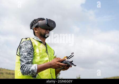 Professioneller Drohnenpilot, der Drohnen steuert, indem er mithilfe der Fernbedienung in die virtuelle Realität schaut – Konzept der modernen Überwachungstechnologie Stockfoto