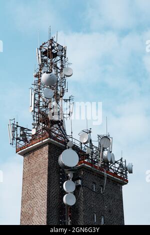 Senkrecht eines Telekommunikationsturms gegen den wolkigen blauen Himmel Stockfoto