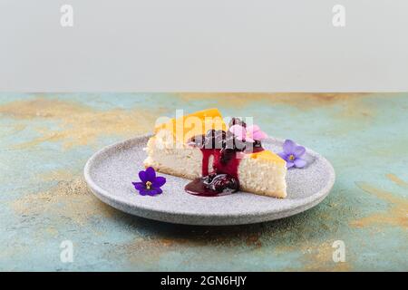 Käsekuchen mit Beerenmarmelade, verziert mit essbaren Blumen Stockfoto