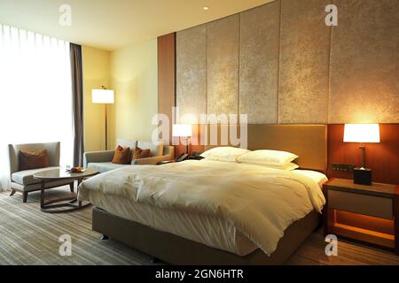 Warmes und gemütliches modernes Schlafzimmer, großes Fenster mit Sofa und Tisch. Stockfoto