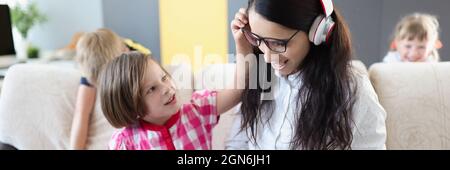 Kleine Kinder hindern ihre Mutter daran, an Laptops zu arbeiten Zu Hause Stockfoto