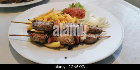 Schweinespieße auf Holzspieße mit Gemüse und Bratkartoffeln. Stockfoto