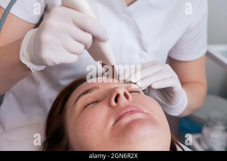 Die Ultraschall-Gesichtsreinigung ist eine moderne und sichere Tiefenreinigung. Frau an der Rezeption der Kosmetikerin während der Spa-Behandlungen. Stockfoto