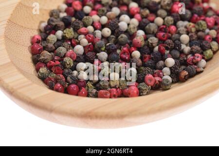 Farbige Pfefferkörner auf einer Holzschale auf weißem Hintergrund. Essen. Stockfoto