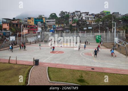 Santiago Atitlan, Guatemala - 29. März 2018: Einheimische Männer spielen Fußball und Basketball auf dem Sportplatz entlang der rustikalen Stadthäuser Stockfoto