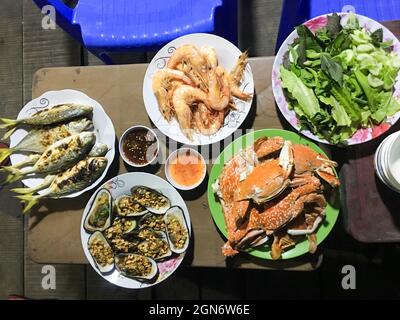 Esstisch mit rohem Gemüse und Meeresfrüchten wie sentinelkrabben, Garnelen, venusmuschel aus Emaille, Muscheln, Fisch Stockfoto