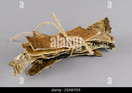 Hundefutter mit Garn auf grauem Hintergrund gebunden. Getrocknete Teller Stockfoto