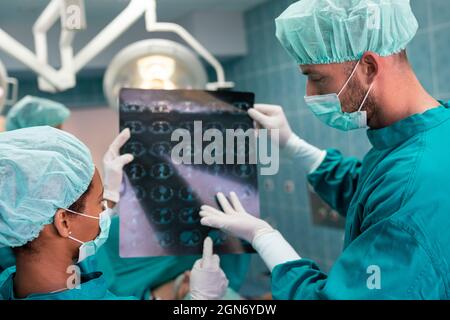 Gesundheitswesen und medizinisches Konzept. Gruppe von Ärzten, die Röntgenaufnahmen vor der Operation betrachten Stockfoto