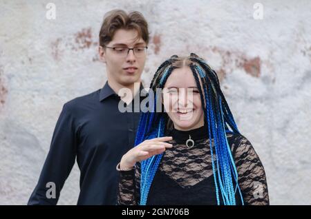 Eine glückliche Frau mit langen blauen Zöpfen. Ein junger Mann steht im Stockfoto