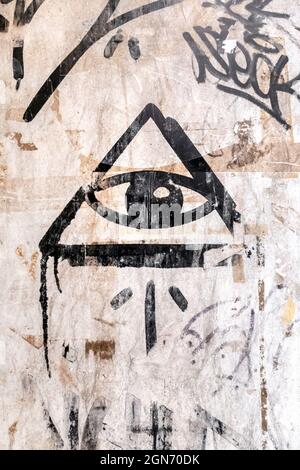 Illuminati-Logo an der Wand gemalt. 'Alle sehenden Auge' Gottes in der heiligen Geometrie Dreieck. Mauerwerk und Illuminaten-Symbol im Dreieck mit Lichtstrahl. Stockfoto