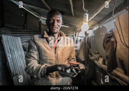 Nairobi, Kenia. September 2021. Victor Otieno (36) hält seine Schlüsselhalter aus recycelten Knochen im African Bone Crafts in Kibera Slums, Nairobi.Eine Gruppe von Handwerkern des African Bone Craft in Nairobis Kibera Slums verwendet recycelte Tierknochen, Hörner und Messingmetalle, um handgemachten Schmuck und Dekorationen zu kreieren, die später an Einheimische und Touristen verkauft werden, die manchmal die Werkstatt besuchen würden. Die African Bones begannen 2006 mit einer Gesamtzahl von 17 Gruppenmitgliedern, die beide vom Handwerksbetrieb abhängig sind, um ihren Lebensunterhalt zu verdienen. Sie haben trotz der Herausforderungen an das Geschäft festgehalten Stockfoto