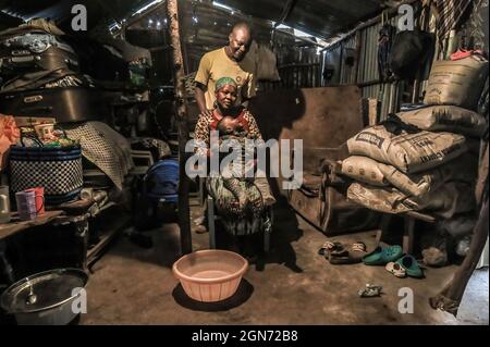 Nairobi, Kenia. September 2021. Charles Owigo (43) ein Mitglied des African Bone Craft nimmt eine Haltung mit seiner Familie in seinem Haus in den Slums von Kibera, Nairobi, ein.Eine Gruppe von Handwerkern des African Bone Craft in den Slums von Kibera in Nairobi verwendet recycelte Tierknochen, Hörner und Messingmetalle, um handgemachten Schmuck und Dekorationen zu kreieren, die später an Einheimische und Touristen verkauft werden, die manchmal die Werkstatt besuchen würden. Die African Bones begannen 2006 mit einer Gesamtzahl von 17 Gruppenmitgliedern, die beide vom Handwerksbetrieb abhängig sind, um ihren Lebensunterhalt zu verdienen. Sie haben trotz aller Herausforderungen an das Geschäft festgehalten Stockfoto